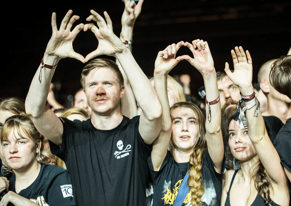 Drei Festivalzuschauer, die ein Herz mit ihren beiden Händen formen und in die Höhe strecken.