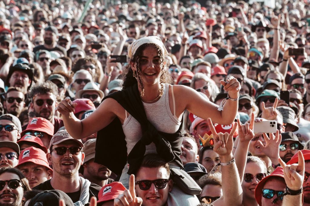 Eine Festivalbesucherin auf den Schultern sitzend in der Publikumsmenge