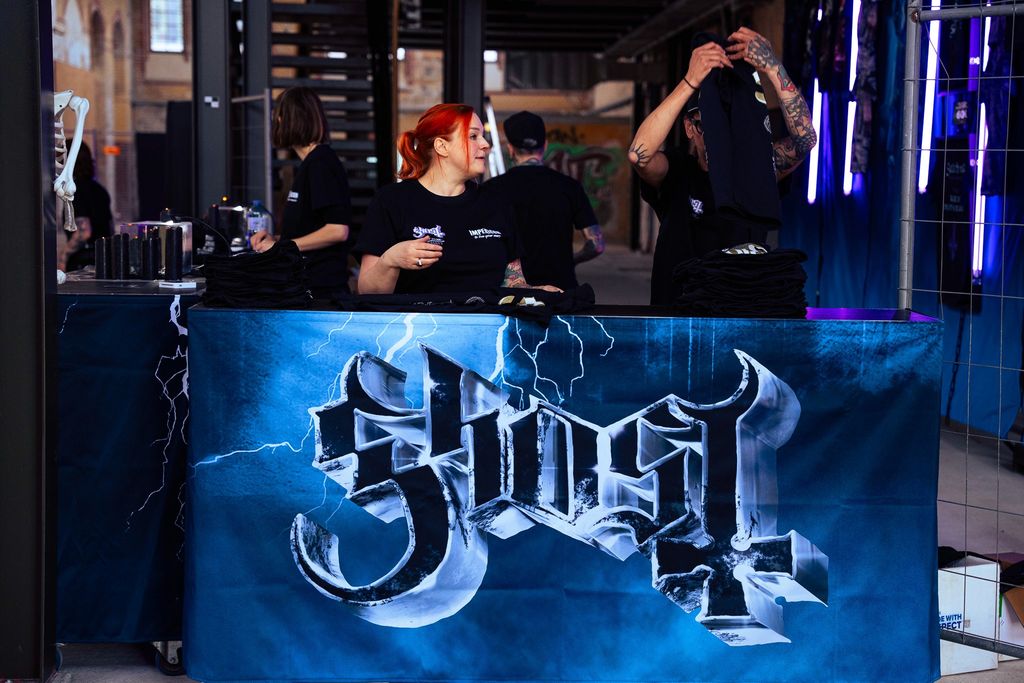 Verkaufsmitarbeiter packen Ware zusammen bei einem Pop-Up-Store der Band Ghost